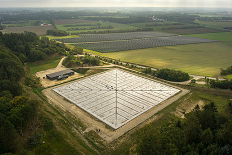 Aerial view of a large solar farm surrounded by fields and forests.