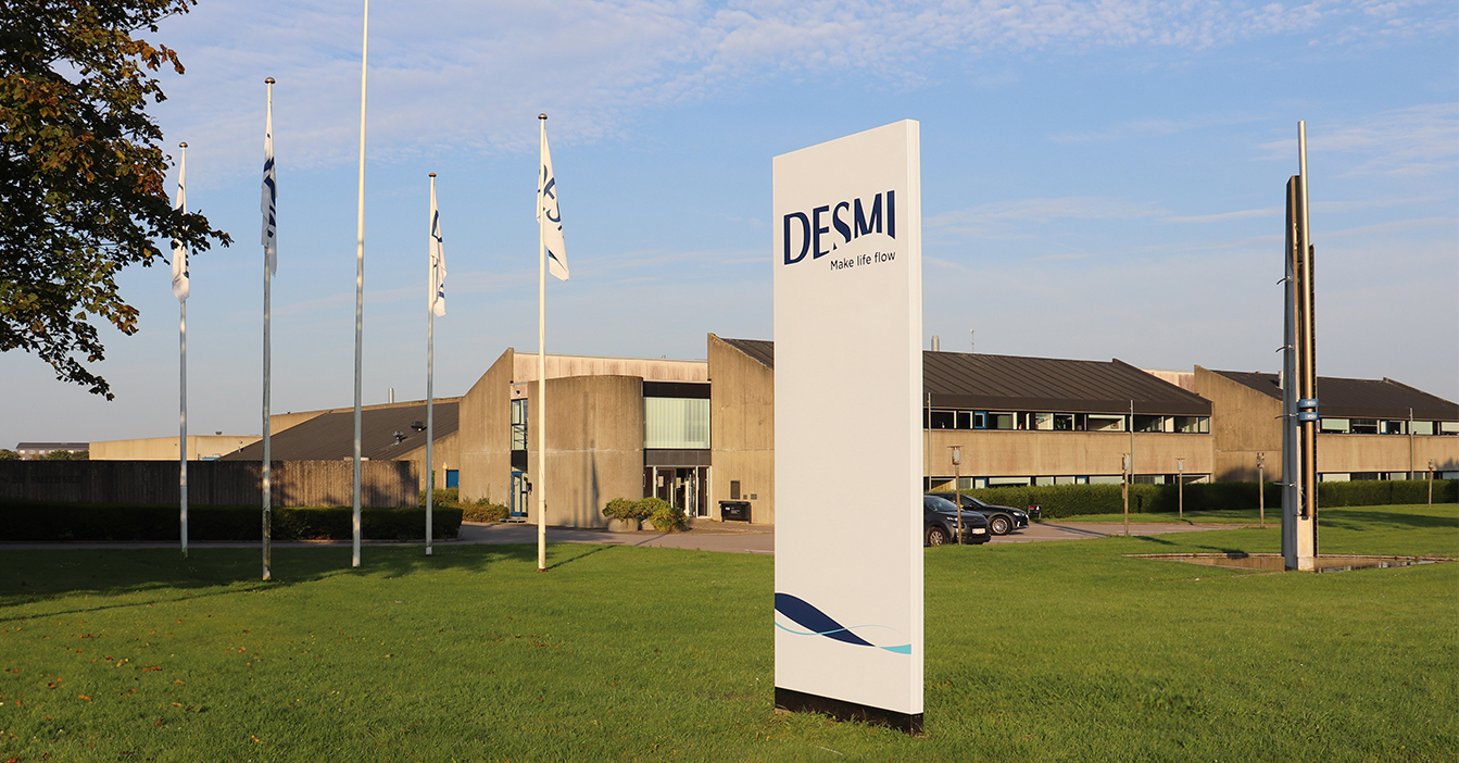 DESMI headquarters with flags and signage on a sunny day.