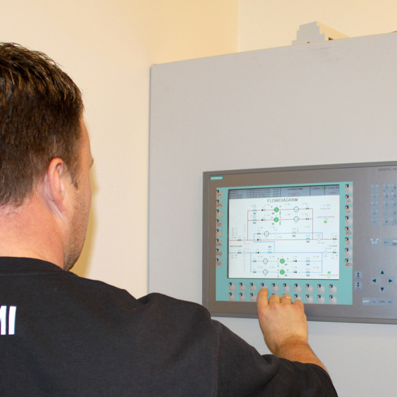 Person operating DESMI control panel displaying a flow diagram on the screen.
